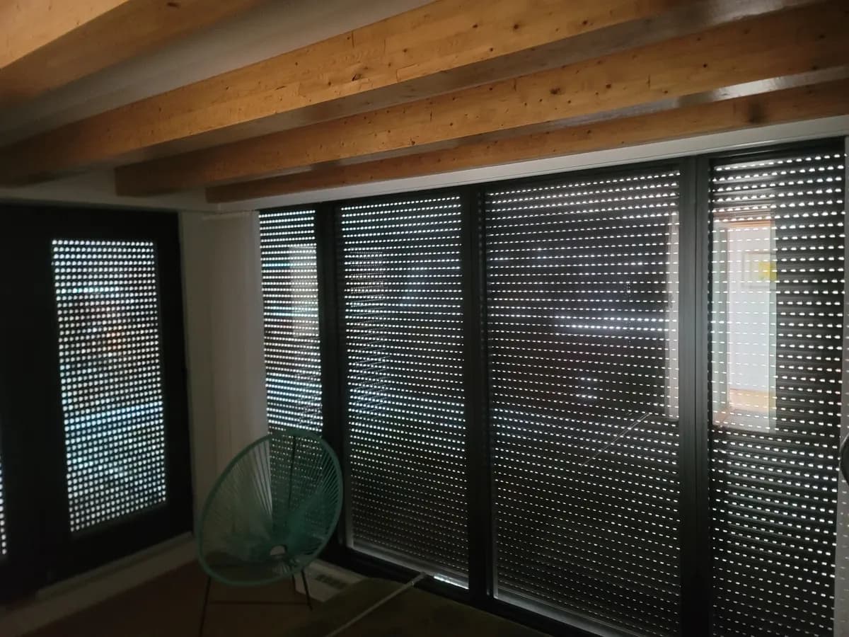Black perforated shutters across a glass wall