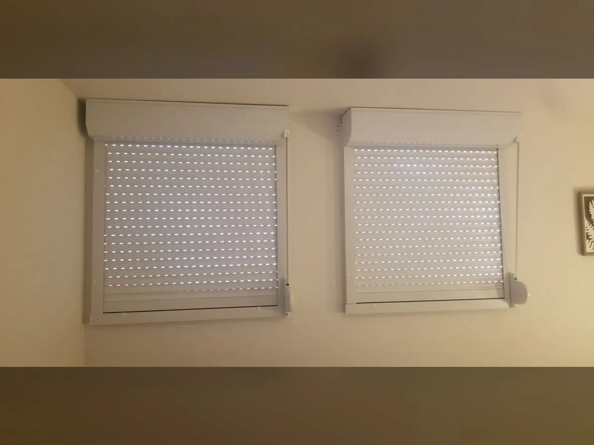 Two perforated shutters closed in a bedroom