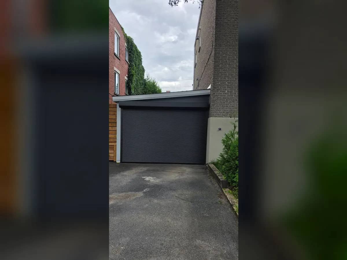 Black roll-up garage door at the end of a driveway