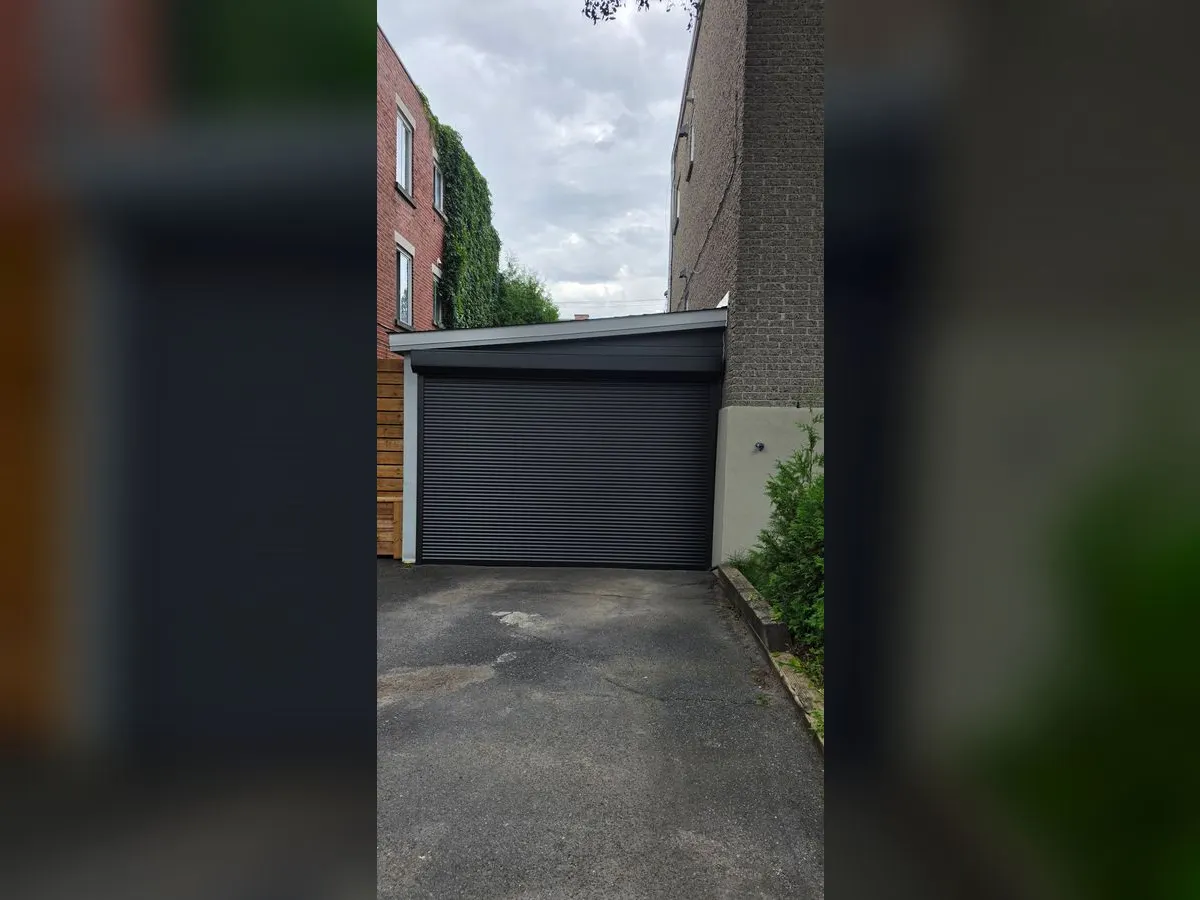 Black roll-up garage door at the end of a driveway